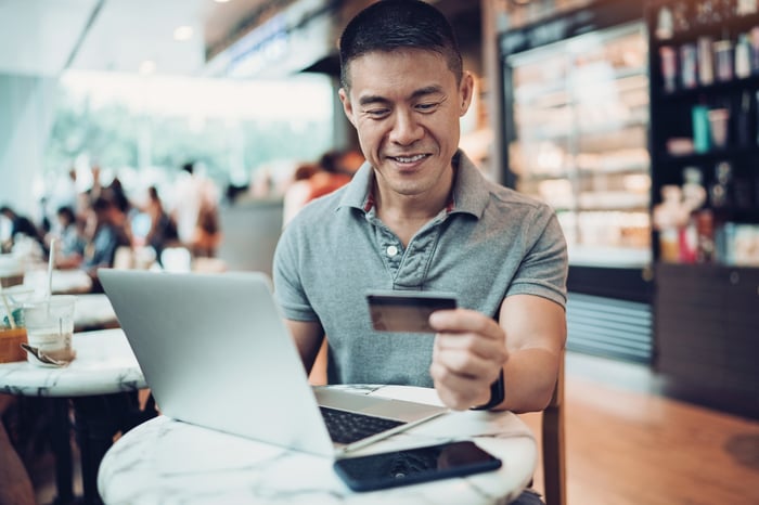 An e-commerce customer shops online while holding a credit card.