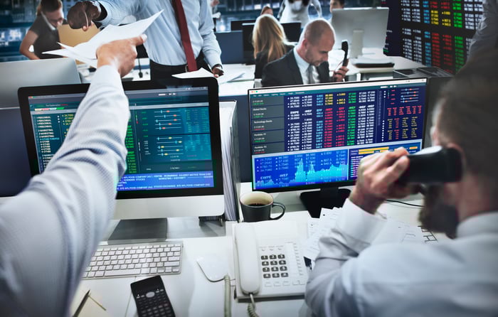 Professional stock traders on the phone while looking at quotes on their computer screens.