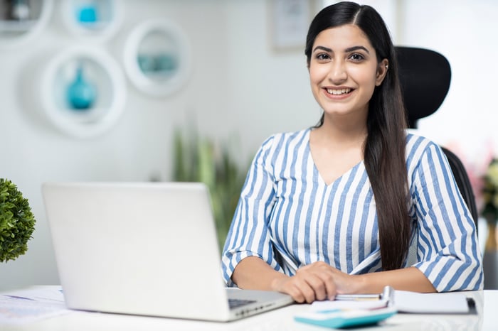A smiling person at a laptop.