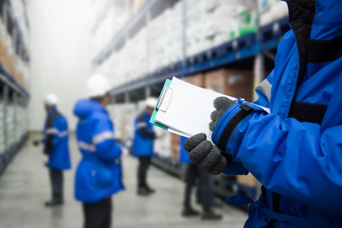 People in blue coats working in a cold-storage warehouse.