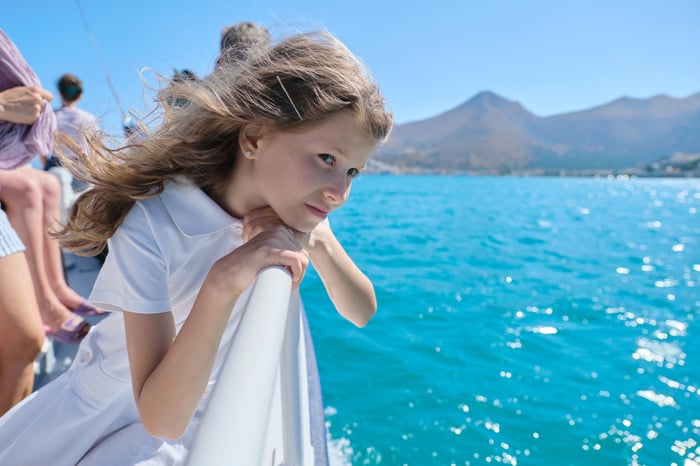 Child looking pensive while leaning over railing on a cruise ship.