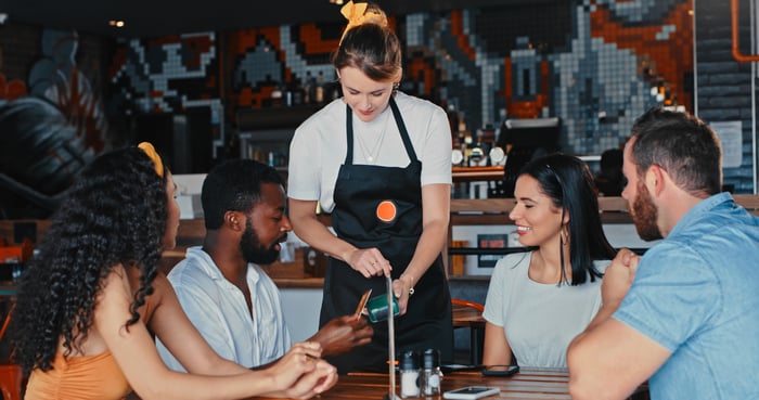 A group of friends make a digital purchase at a restaurant.