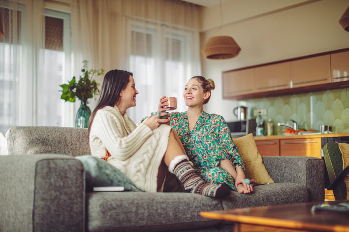 Two people sitting on a couch drinking coffee in pajamas.