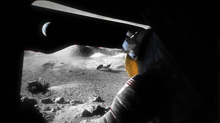 Astronaut peers out of a lander at the surface of the moon.