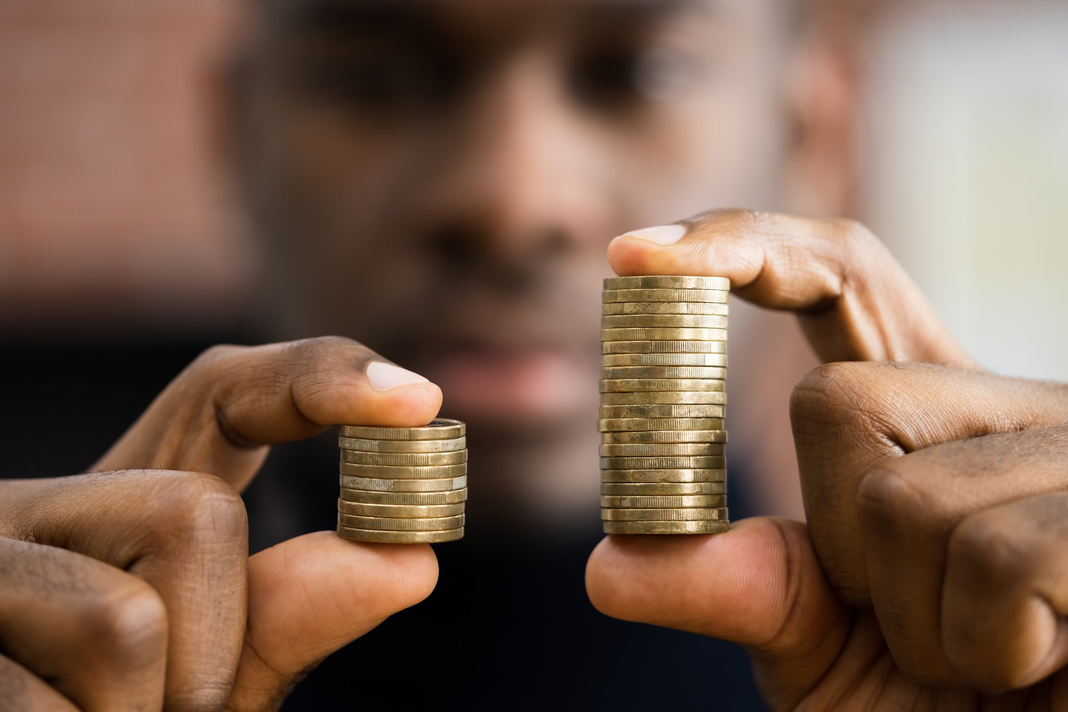 A person holding two stacks of coins, one double the size of another.