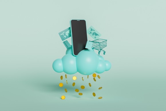A cloud with money falling from it, with a smartphone and a shopping cart on top.
