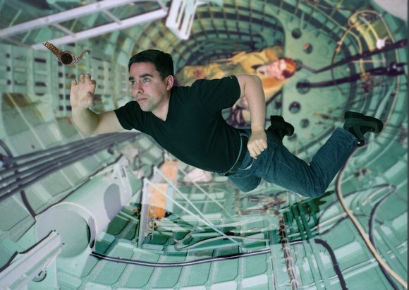 Person floating in weightlessness in a space station corridor.