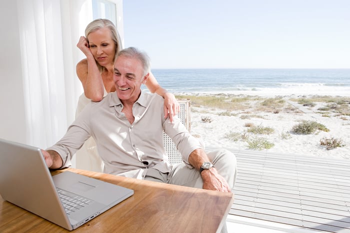 Couple looking at laptop with a beach in the background.