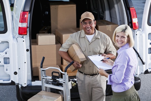 A package delivery driver and recipient smiling.