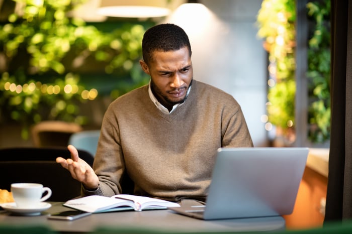 A person with a confused expression at a laptop.