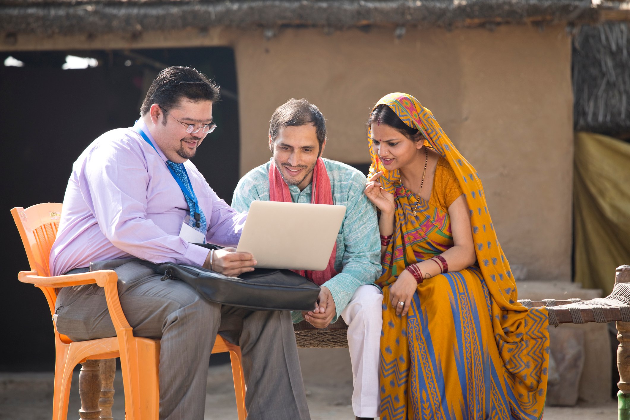 A finance person explaining products on a laptop to village natives in rural India.