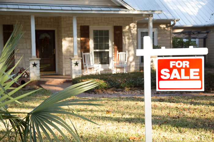 A house with a for sale sign in the front yard.