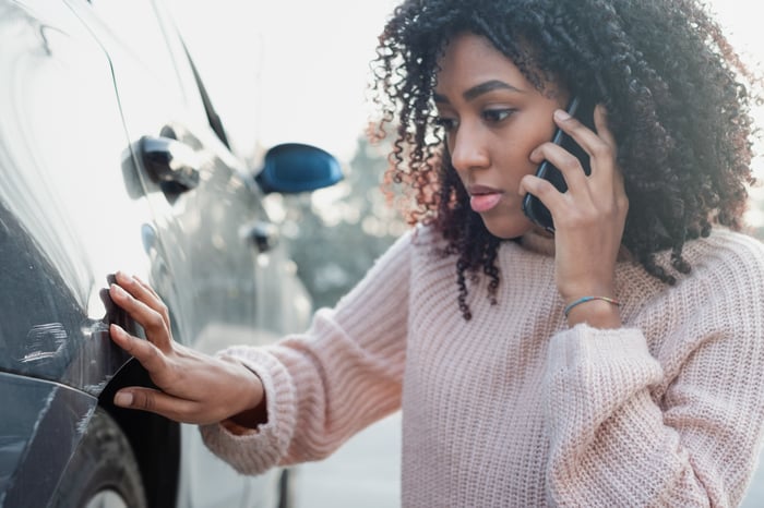 A woman on the car looks at damage to her car.