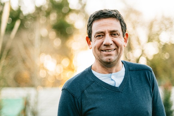 A smiling person wearing a sweater.