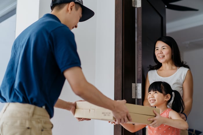 Deliveryman hands package to a child with her mother. 