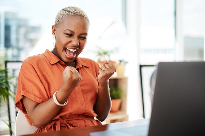 Person celebrating while looking at a computer. 