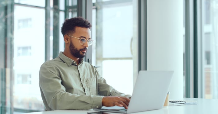 A person with a serious expression at a laptop.