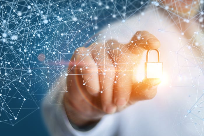 A person holding a glowing golden lock that's surrounded by a lattice-like structure.