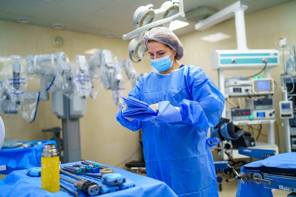 A surgical technician prepares an operating room that features a robotic surgical suite.