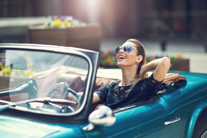Fashionable person sitting in luxury retro car with sunglasses.