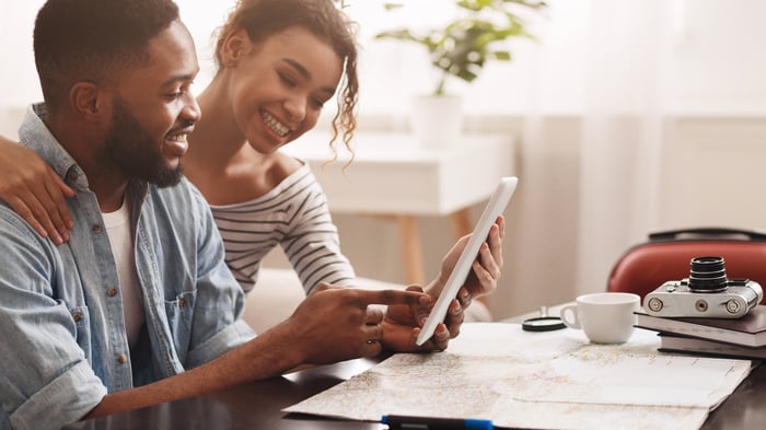 Two people smile and look at a tablet.