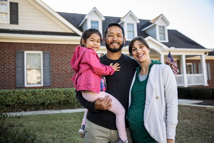 Happy family in front of a house.
