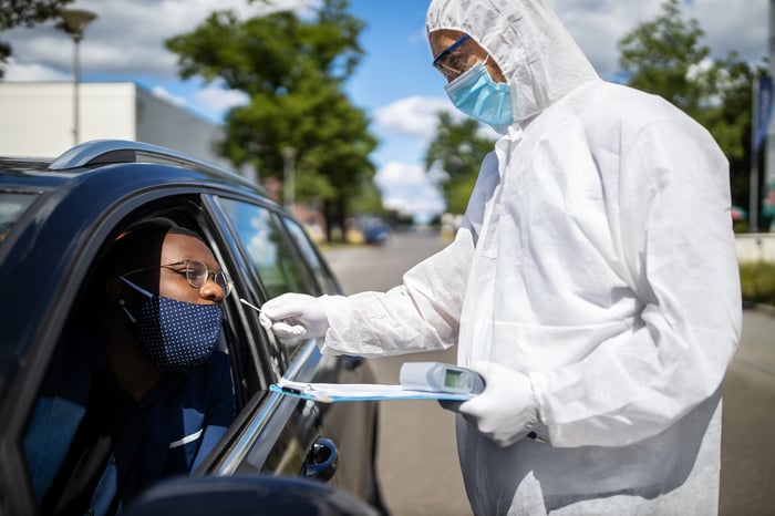 Person administering a COVID-19 test in a drive-through.