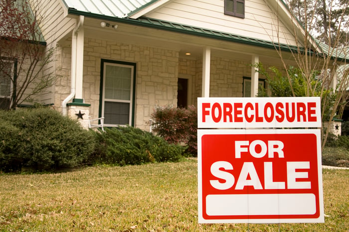 A house with a foreclosure for sale sign in front of it.