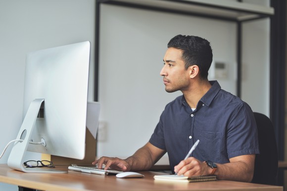 A person at a computer taking notes.