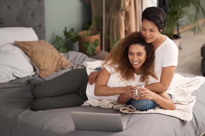 Two people in a bed looking at a computer.