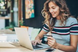 person holding credit card and using laptop