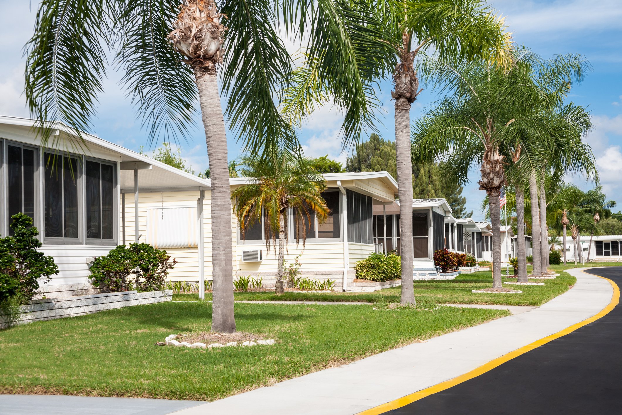 A manufactured home park with a palm tree lined street.