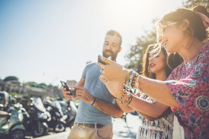 A group of friends takes and shares photos with their smartphones.