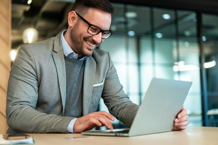 A smiling person at a laptop.