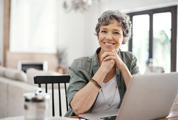 A smiling person at a laptop.