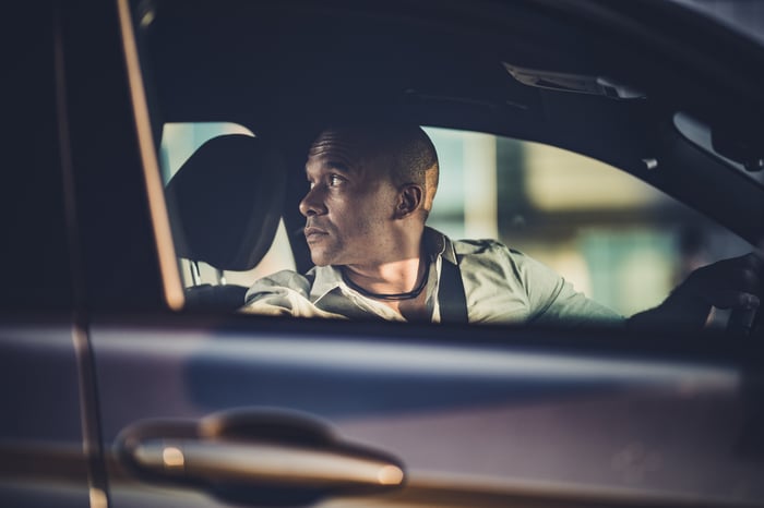 A man reverses his car while turning to look in the rear window.