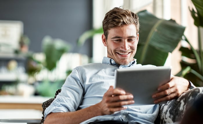 A smiling person holding a tablet.