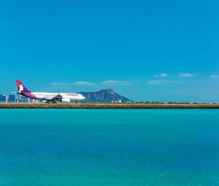 A Hawaiian plane on the runway with Diamond Head behind it.