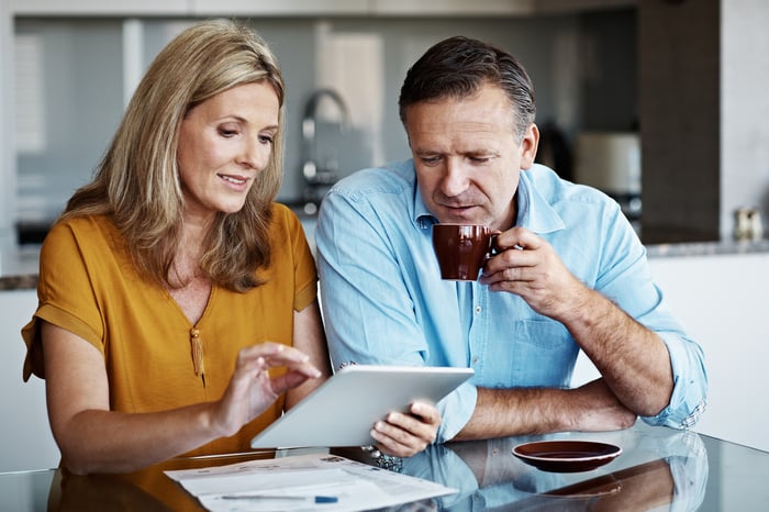 Two people at a table using a tablet.