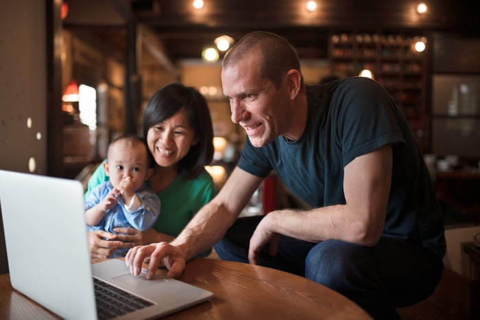 couple with baby looking at laptop computer and smiling