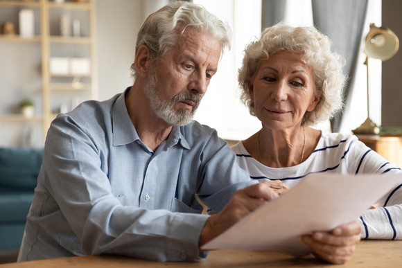 Two people read a form while sitting at a table in their home.
