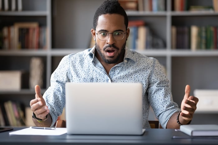 A person looking at a computer screen with a look of unpleasant surprise.