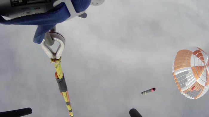 Rocket Lab's helicopter-view of its capture hook approaching the parachute above a descending Electron rocket first stage. 