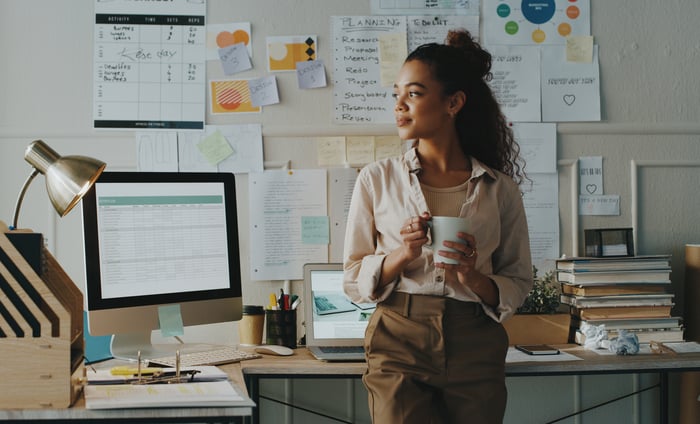 A person in an office looking to the side and holding a cup.