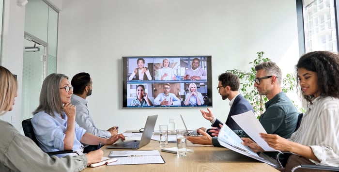 Employees on video conference call in meeting room.