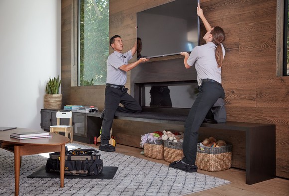 Best Buy Geek Squad members installing a TV.