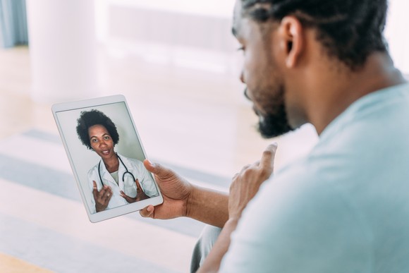 Person holding a tablet, conferencing with a doctor.