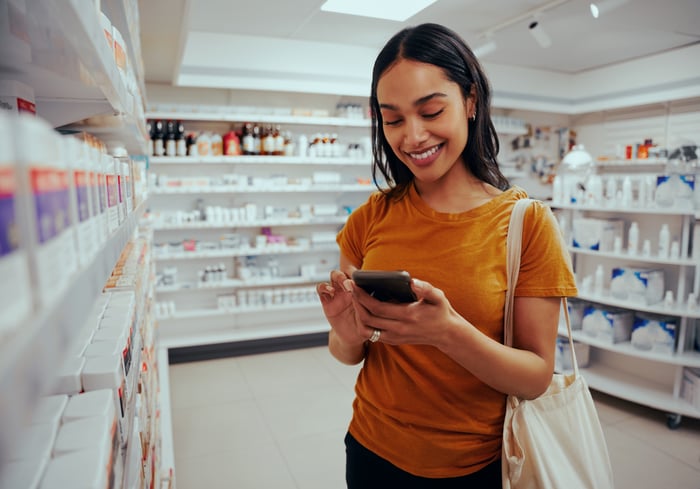 A customer uses their smartphone while standing in a pharmacy.