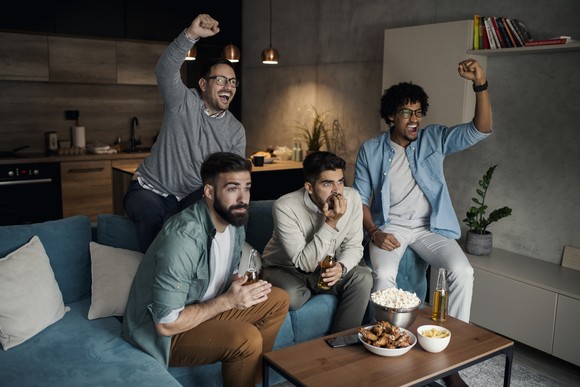 A group of people watching television and cheering.