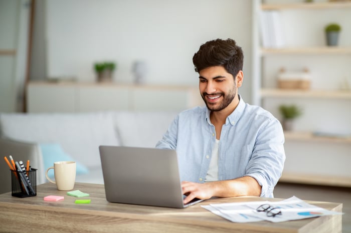 A smiling person at a laptop.